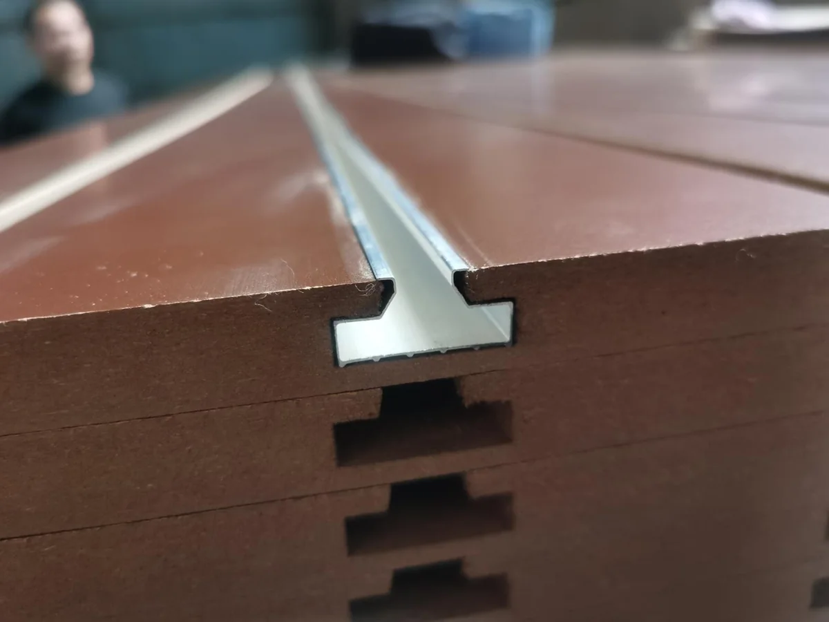 Aluminum insert seated in the machined slot of a brown melamine MDF panel