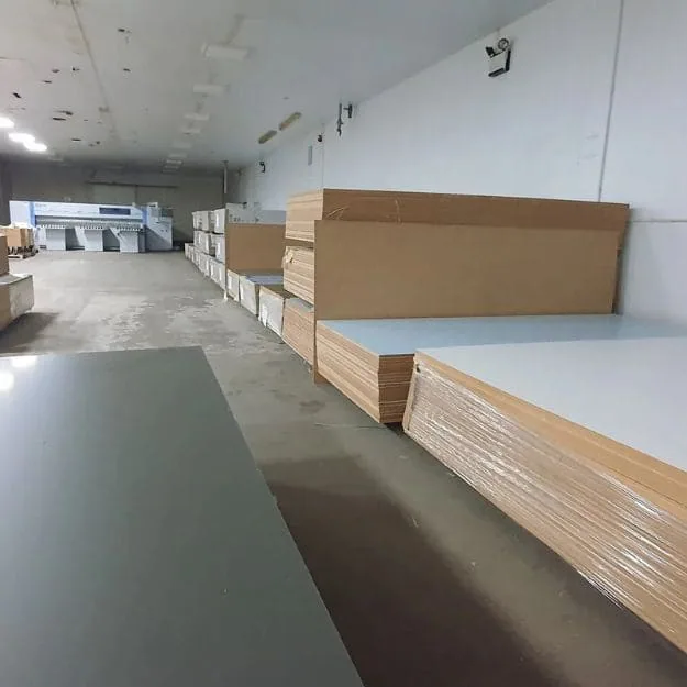 Light-faced panel stacks and wrapped board bundles inside a storage room.