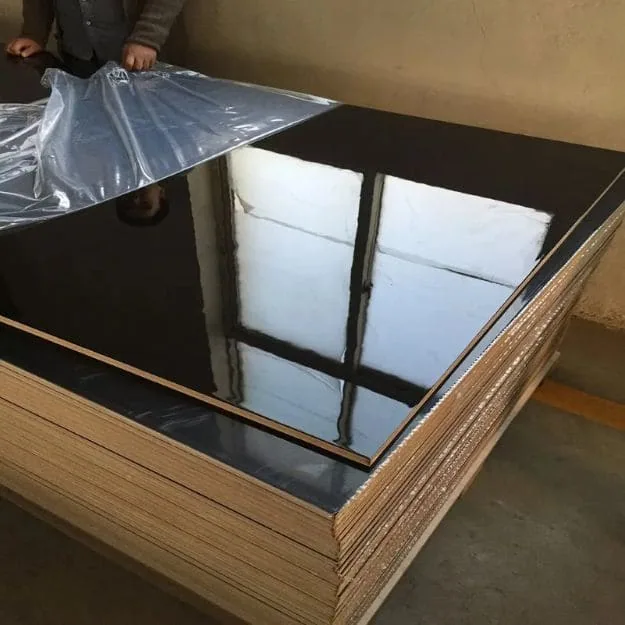 Glossy dark-faced panel sheets reflecting windows, with protective film lifted from the surface.